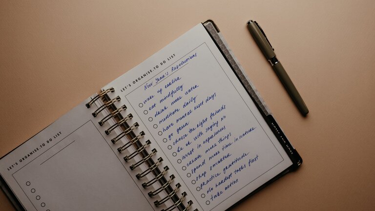 Foto eines Notizbuchs auf einem weissen Tisch, in dem eine To-Do-Liste aufgeführt ist. | © pexels