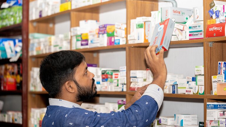Foto eines Apothekers, der gerade eine Schachtel mit Medikamenten aus einem Regal nimmt. | © pexels
