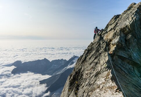 Person klettert eine steile Felswand hoch. | © unsplash