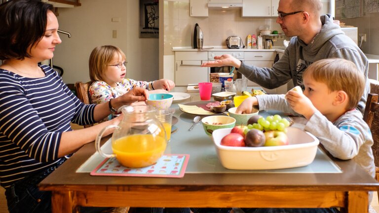 Eine Familie mit einem Kind mit Behinderung sitzt beim Abendessen zusammen. | © Gesellschaftsbilder.de