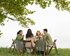 Ein Tisch im Grünen an dem vier Freunde sitzen und sich unterhalten. | © Pexels / Ron Lach