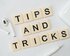 Steinchen mit der Aufschrift "Tips and Tricks", die aneinander gereiht sind, daneben ein Paar Kopfhörer und ein weisser Kugelschreiber. | © Pixabay
