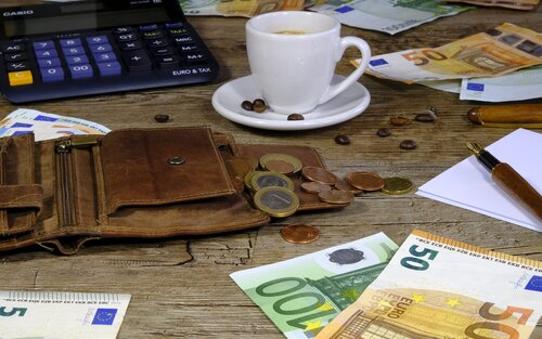 Kaffee-Tasse, Portemonnaie, Taschenrechner, Münzen und Noten auf einem Tisch.  | © pixabay