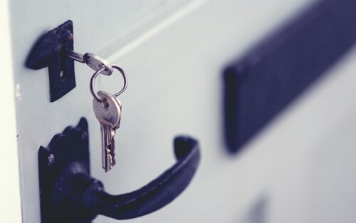 Nahaufnahme eines schwarzen Türschlosses, mit eingestecktem Schlüssel. | © unsplash