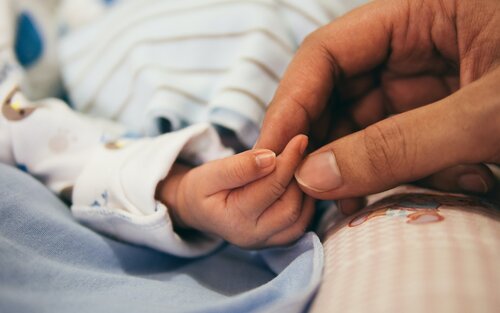 Foto von zwei Fingern, die die kleine Hand eines Babys halten. | © unsplash