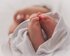 Kleine Babyfüsse schauen aus einem Tuch heraus, in das das Baby eingewickelt ist | © unsplash