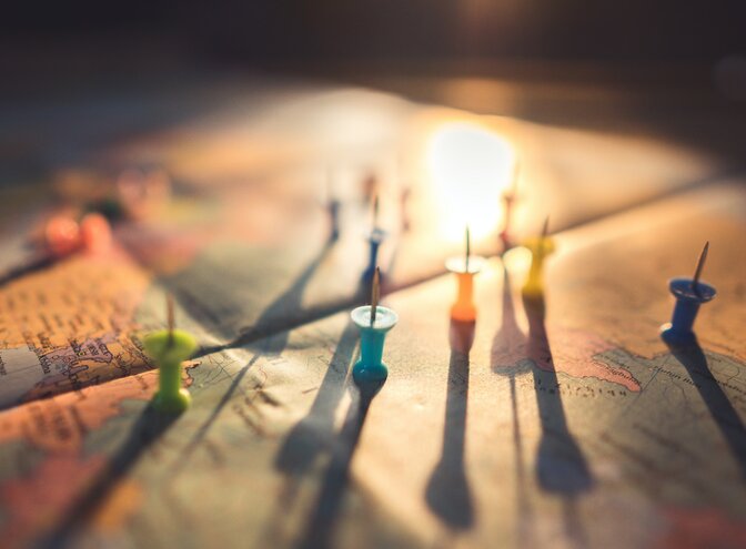 Nahaufnahme einer Weltkarte mit verschiedenfarbigen Stecknadeln auf der Karte. | © Pexels / Aksonsat Uanthoeng