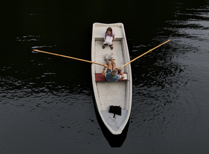 Un bateau sur lequel sont assis un homme et une petite fille, l'eau est sombre. | © pexels