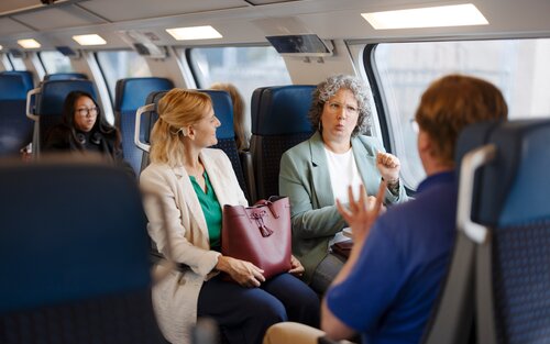 Drei Reisende im Zugabteil, die sich in Gebärdensprache unterhalten. | © © SBB CFF FFS