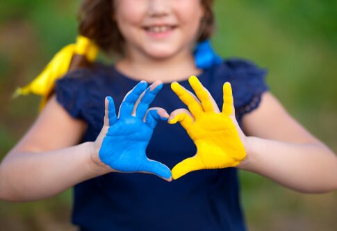 Ein Mädchen, dessen Hände in blau und gelb angemalt sind, formt ein Herz. | © pexels
