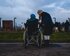 Person im Rollstuhl mit unterstützender Person vor Zaun. | © unsplash