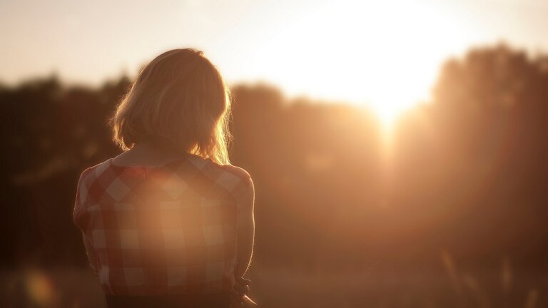 Eine Frau schaut bei Sonnenaufgang in die Ferne. | © pixabay