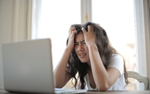 Eine Frau im weissen Shirt sitzt am Laptop und rauft sich die Haare. Sie ist offensichtlich gestresst. | © pexels