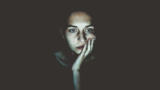 Frau, die im Dunkeln vor einem hellen Bildschirm sitzt | © unsplash
