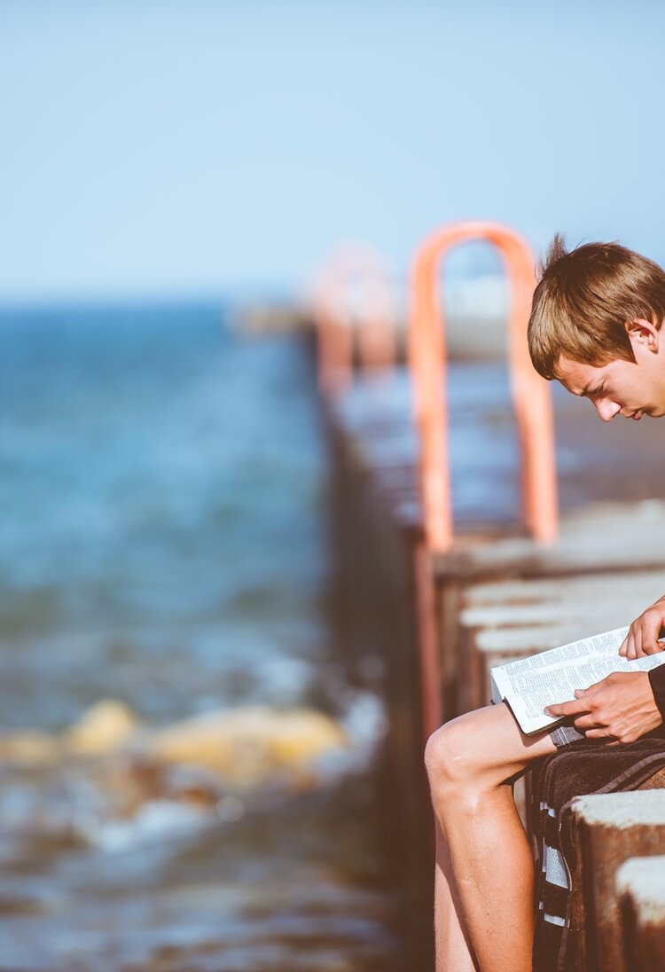 Garçon lisant seul au bord de la mer | © unsplash