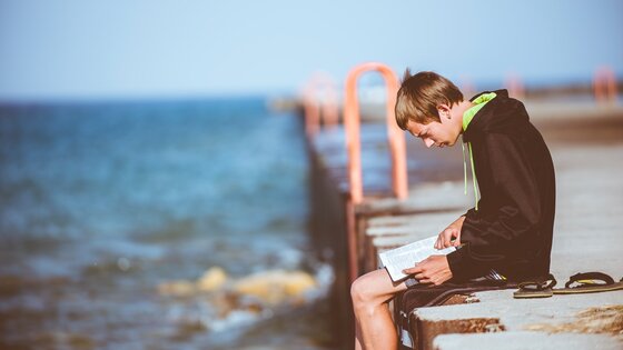 Junge liest alleine an einer Küste | © unsplash