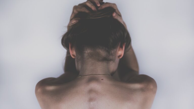 Eine Frau, die sich am Kopf hält und offensichtlich an schmerzen leidet | © pixabay