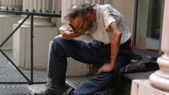 Ein älterer ungepflegter Herr sitzt auf der Treppe vor einem Haus und weint.  | © unsplash