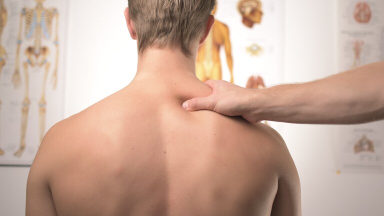 Rücken eines Mannes, während der Physiotherapie. | © unsplash