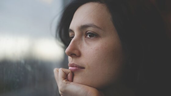 Nahaufnahme des Gesichts einer Frau, die nachdenklich aus dem Fenster schaut | © pixabay