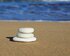 Drei runde Steine mit von oben nach unten ansteigender Grösse, die übereinander auf Sand mit dem Meer im Hintergrund gestapelt sind. | © pixabay