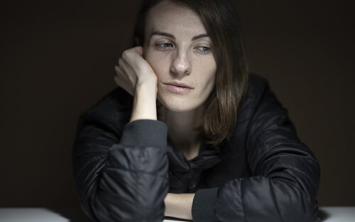 Foto einer Frau, die sichtlich müde an einem Holztisch sitzt und den Kopf auf die Hand aufstützt. | © pexels