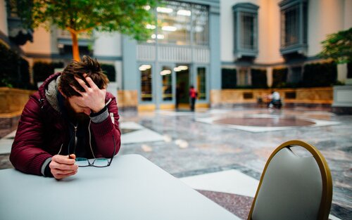 Foto eines Mannes, der in einem Restaurant sitzt und den Kopf in die Hände stützt. Er sieht sehr verzweifelt aus. | © pexels