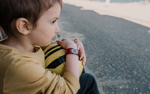 Garçon tenant un ballon de football et portant un bracelet d'urgence. | © unsplash
