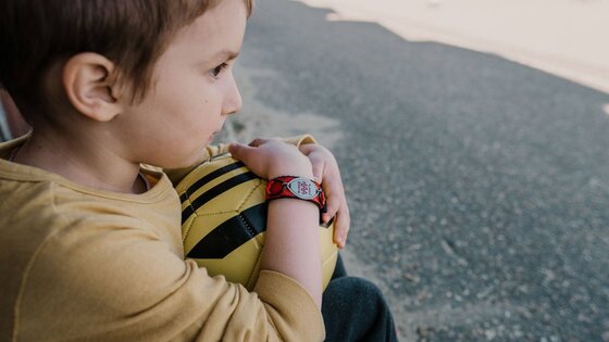 Junge hält einen Fussball und trägt ein Notfallarmband. | © Unsplash