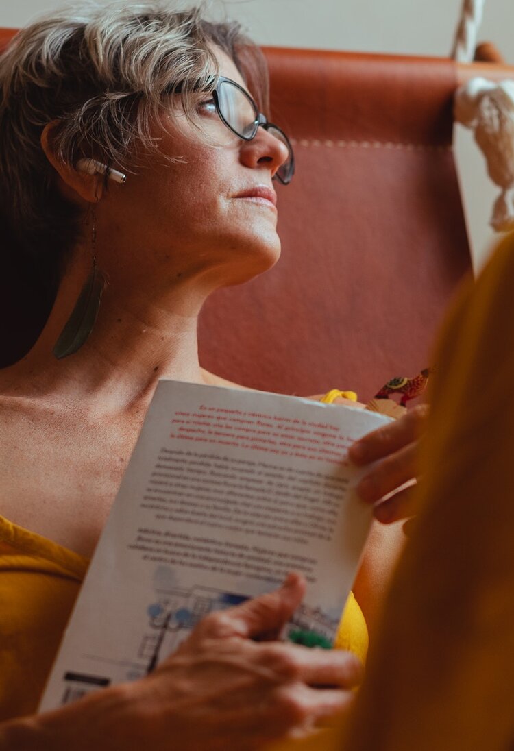 Eine Frau hält ein Buch in den Händen und schaut nachdenklich in die Ferne. | © Pexels / Los muertos crew