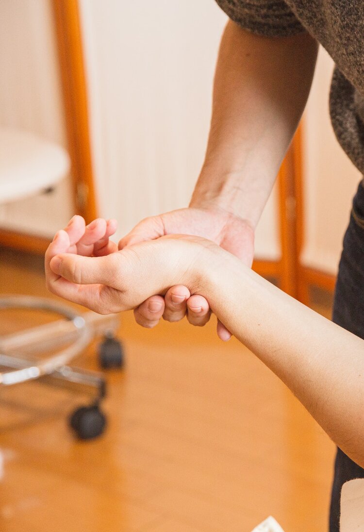 Ein Mann liegt auf einer Behandlungsliege und der Therapeut führt Übungen mit der Hand des Patienten aus. | © Pexel / Ryutaro Tsukata