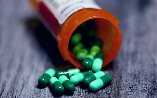 Grüne Kapseln in einer Medikamentendose. | © unsplash