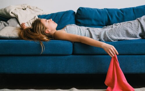 Eine Frau liegt müde auf dem Sofa und starrt erschöpft an die Decke. | © pexels