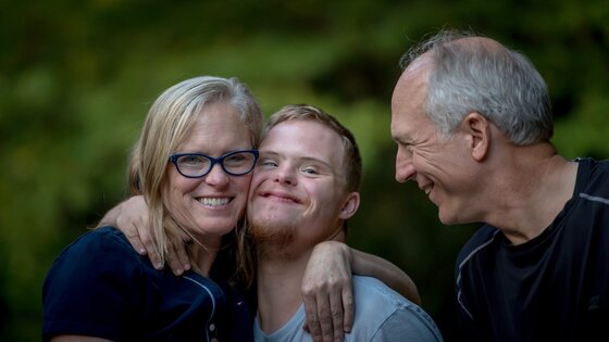 Une famille avec un fils avec une déficience intellectuelle sourit à la caméra. | © unsplash
