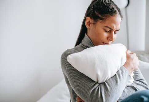 Eine Frau mit Schmerzen drückt fest ein Kissen an sich. | © Pexels / Alex Green