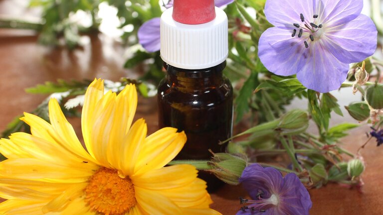 Eine kleine Tropfflasche und im Hintergrund Blumen | © pixabay