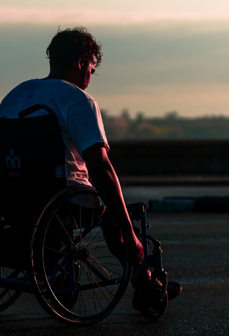 junger Mann im Rollstuhl, von hinten bei Abendstimmung | © unsplash