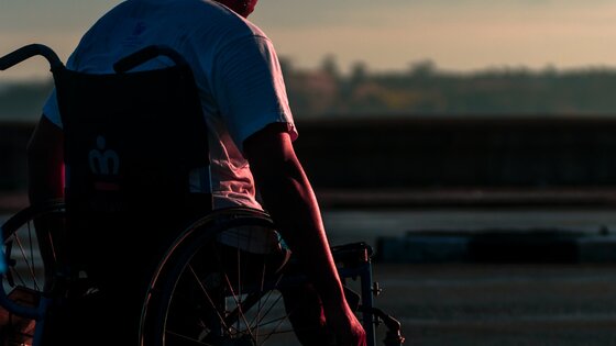 junger Mann im Rollstuhl, von hinten bei Abendstimmung | © unsplash
