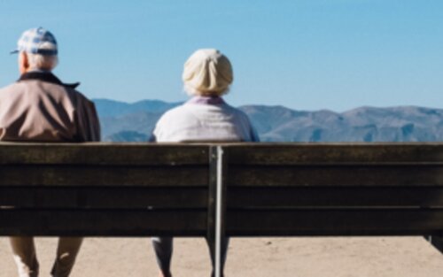 Mann und Frau sitzen auf einer Bank mit Blick auf Meer.  | © unsplash