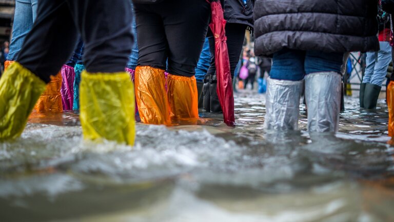 Menschen stehen im Wasser aufgrund einer Überflutung.  | © unsplash