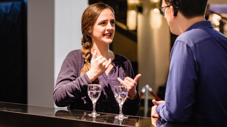 Ein Paar spricht in Gebärdensprache an einer Bar. | © Andi Weiland/Gesellschaftsbilder.de
