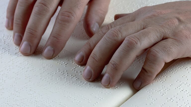 Mann liest einen Text mit Brailleschrift.  | © pixabay
