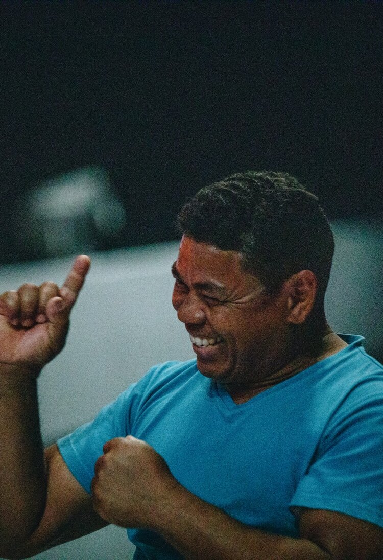 Ein Mann in einem blauen T-Shirt lacht und streckt seinen rechten Zeigefinger nach oben.  | © Unsplash