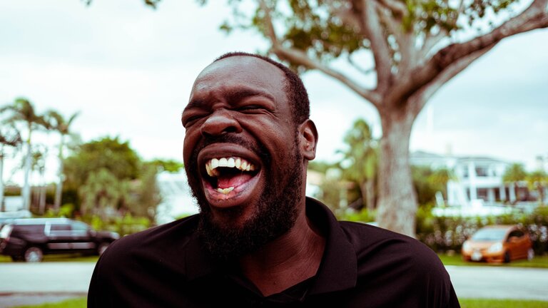 Un homme rit à gorge déployée avec sa bouche ouverte. | © unsplash
