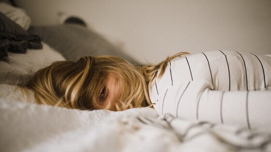 Frau, die auf dem Bett liegt und nicht schlafen kann | © unsplash