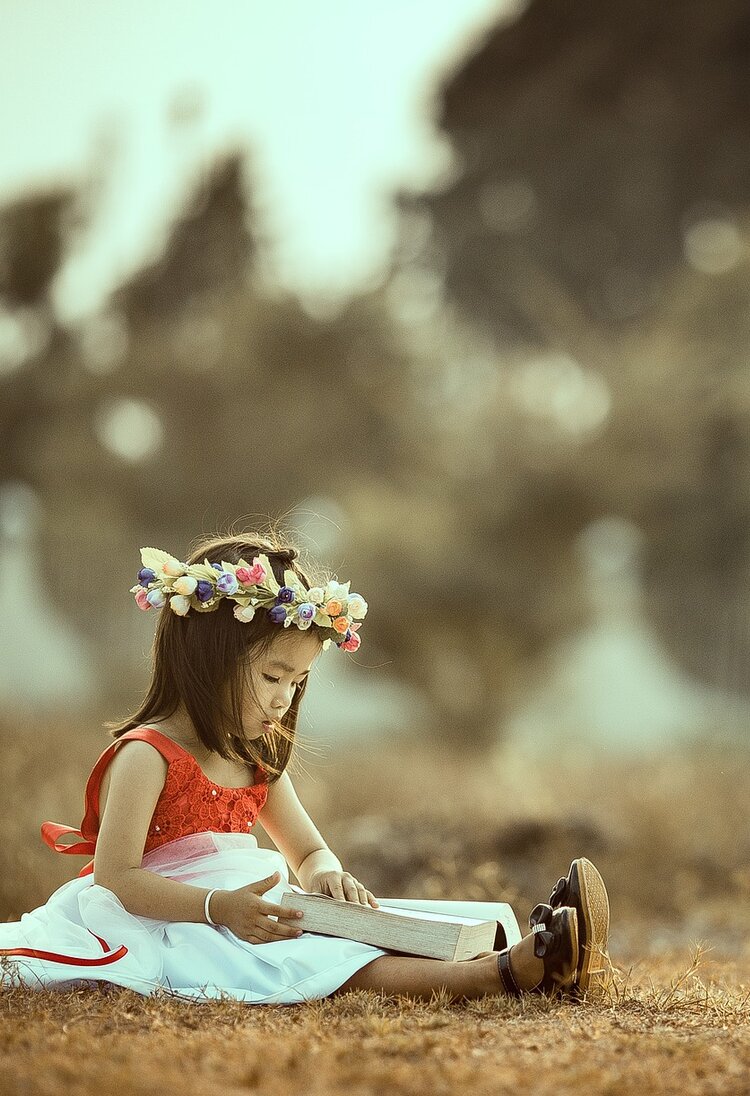 Kleines Mädchen liest draussen ein Buch.  | © Pixabay