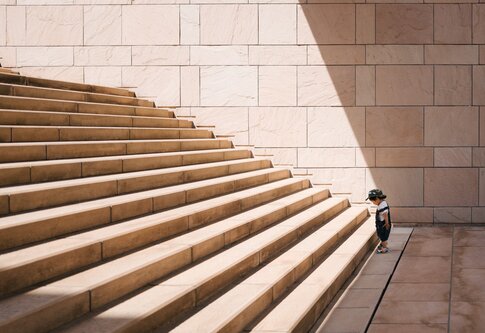 Petit garçon devant de grandes marches d'escalier | © unsplash