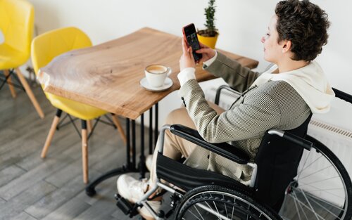 Eine Frau im Rollstuhl checkt ihr Smartphone. | © pexels