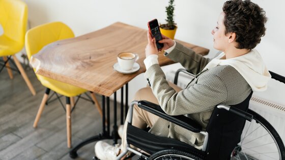 Eine Frau im Rollstuhl checkt ihr Smartphone. | © Pexels / SHVETS production