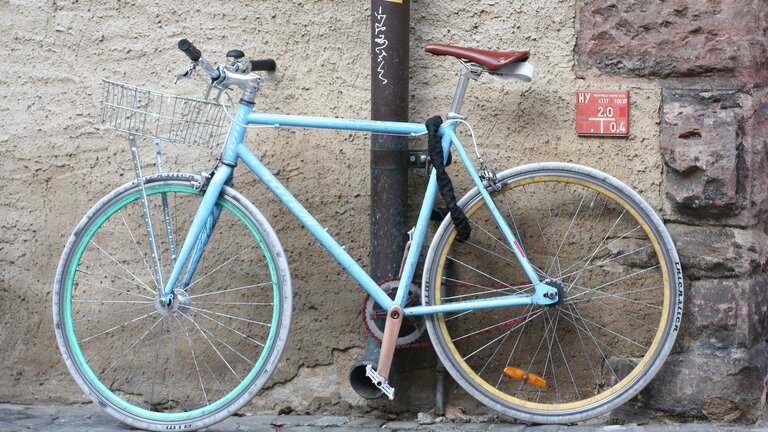 blaues Fahrrad, das an einem Abflussrohr angekettet ist | © pixabay